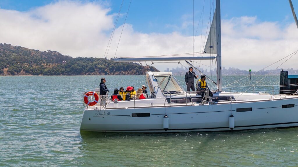 A group enjoying a sailing adventure on a sailboat with scenic coastal views.