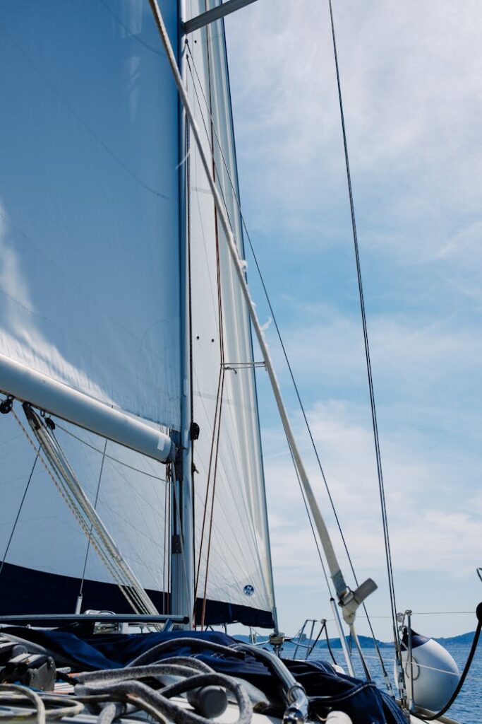 Vertical shot showcasing the mast and sail of a sailboat against a clear blue sky.