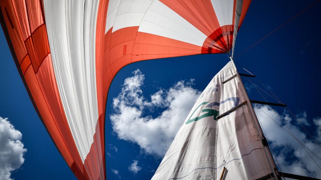 Dynamic view of sails against blue sky, capturing the essence of a perfect sailing day.